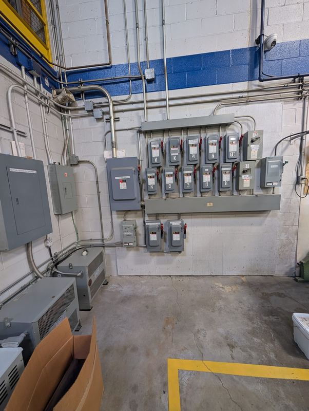 Wall-mounted bank of fused disconnect switches and distribution equipment in an industrial electrical room.