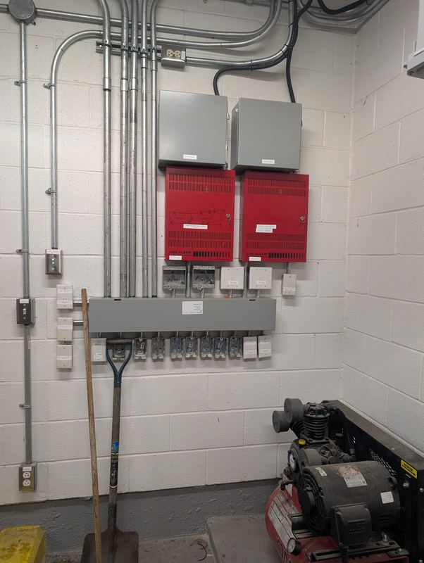 Fire alarm power supply panels with conduit runs feeding a terminal/junction bar.
