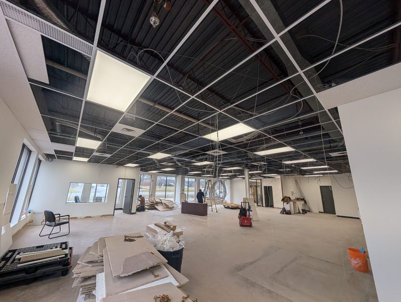 Office renovation in progress with new ceiling grid and light fixtures being installed.