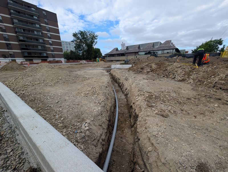 Underground conduit laid in an open trench at a construction site.