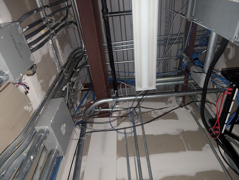 EMT conduit runs, junction boxes and blue data cabling above a commercial ceiling