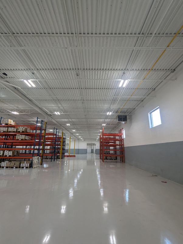 Bright warehouse interior lit by rows of LED fixtures above storage racking